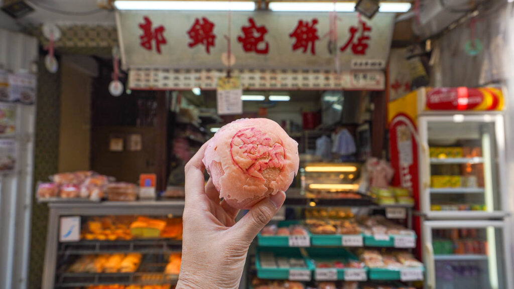 Lotus filled pastry held up in front of the Kwok Kam Kee Shop