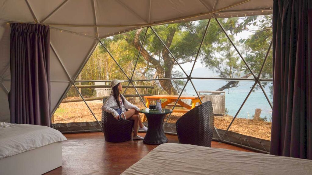 Lady looking out of Saiyuen's Stargazing Geodesic Dome in the day, at the sea and nature that surrounds it