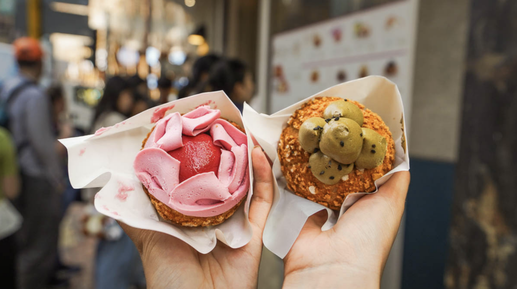 Hands holding up the Strawberry Mousse and Hojicha flavours of Bolo Bun from Owl cafe.