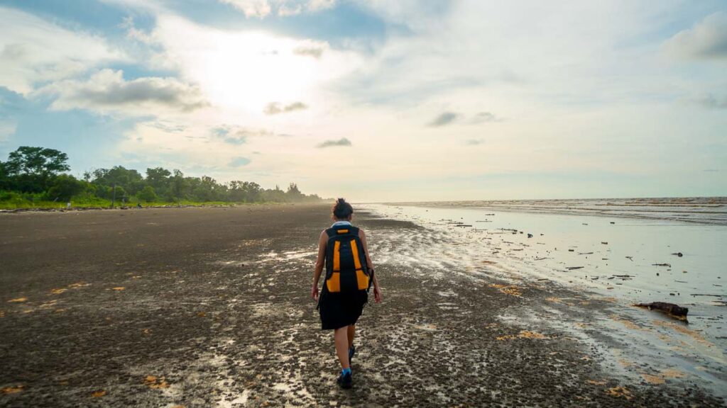 Woman walking along Mukah Beach - Sarawak guide