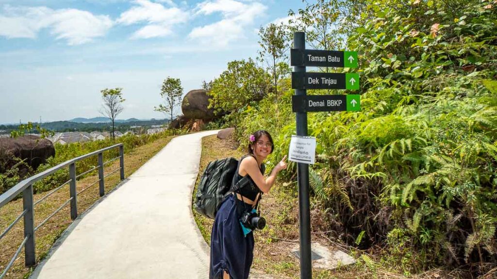 Female hiker pointing to a directional pole at Kangkar Pulai
