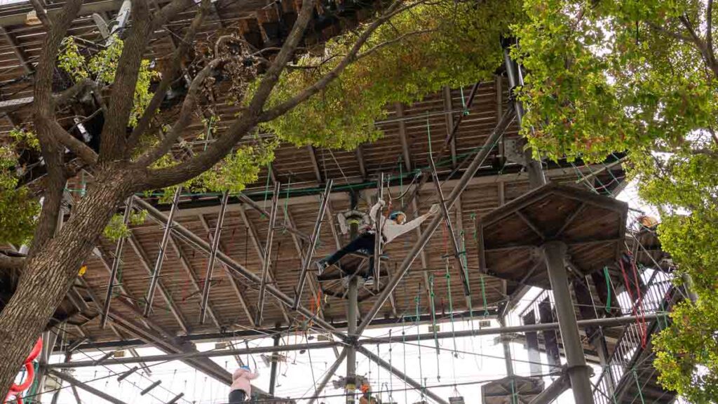 A person tackling the high elements obstacle course at Magic Jungle at North Bund Greenland - North Bund Greenland