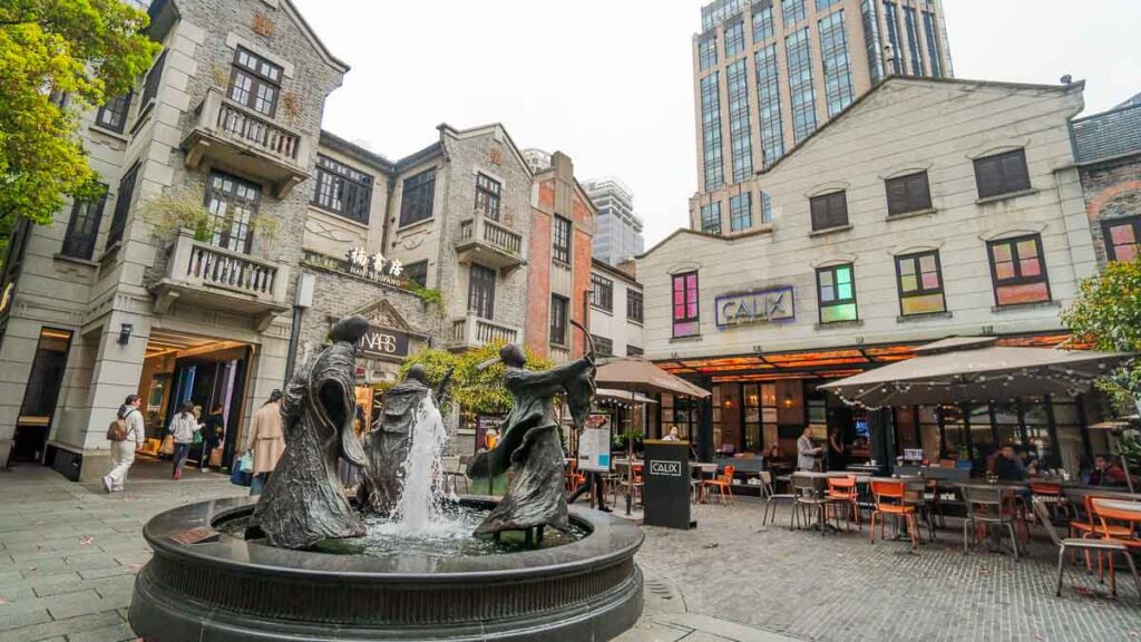 A square in Xintiandi with a fountain and traditional-looking buildings with shops - Shanghai tourist spots