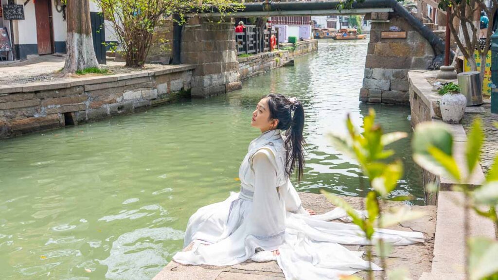 A girl sitting by the canal in her white hanfu at Zhujiajiao - Zhujiajiao