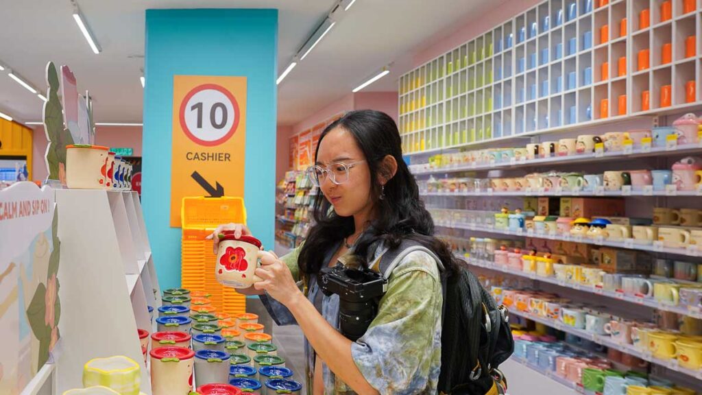 Person holding a ceramic cup with a vibrant red flower design.