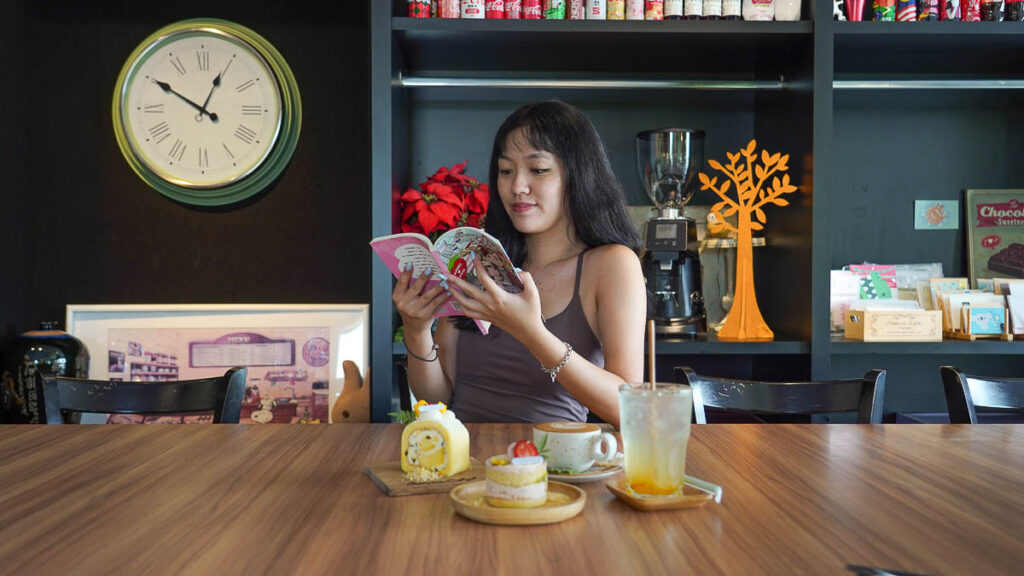 girl reading a book with dessert in front of her