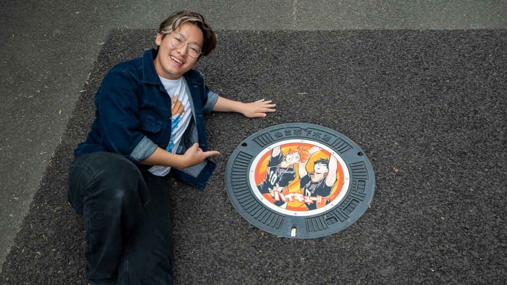 Boy lying in front of Haikyu!! manhole cover, Tomizawa park - Tohoku Summer Itinerary