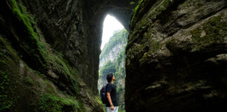 5 Scenic Day Trips under 3hrs Away from Chongqing — Wulong Karst, Dazu Rock Carvings, Black Mountain Valley and More Person looking at the Three Natural Bridges at Wulong Karst