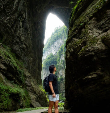 5 Scenic Day Trips under 3hrs Away from Chongqing — Wulong Karst, Dazu Rock Carvings, Black Mountain Valley and More Person looking at the Three Natural Bridges at Wulong Karst