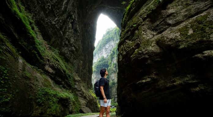 5 Scenic Day Trips under 3hrs Away from Chongqing — Wulong Karst, Dazu Rock Carvings, Black Mountain Valley and More Person looking at the Three Natural Bridges at Wulong Karst