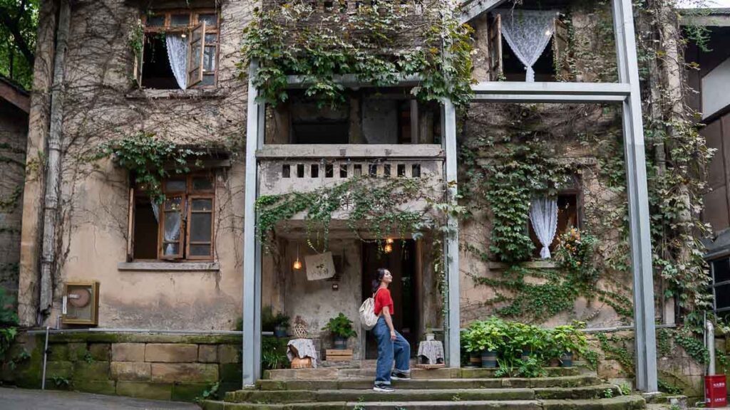 Person posing in front of a preserved old building turned cafe at Jingangbei Ancient Village