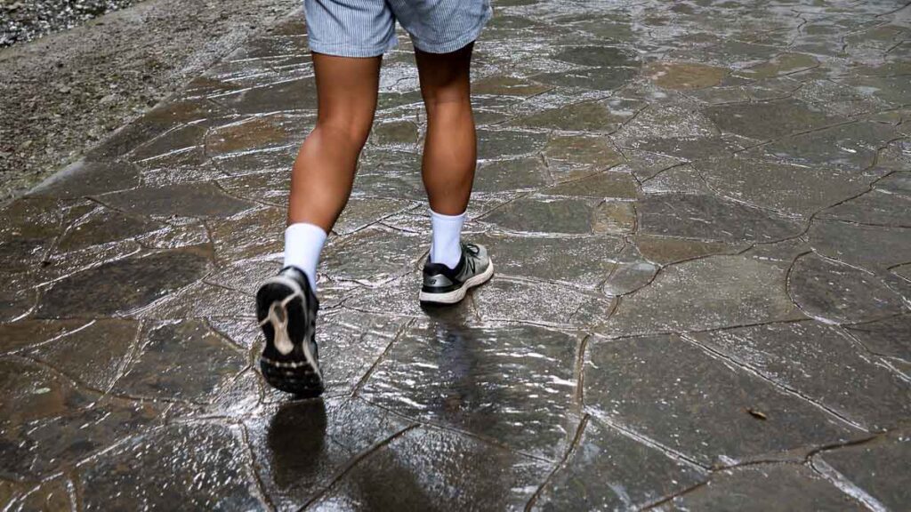 Close-up of person's shoes, walking on wet ground of Three Natural Bridges Trail