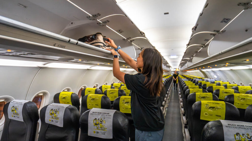 Girl putting bag in on overhead bin on a scoot flight - Davao things to do