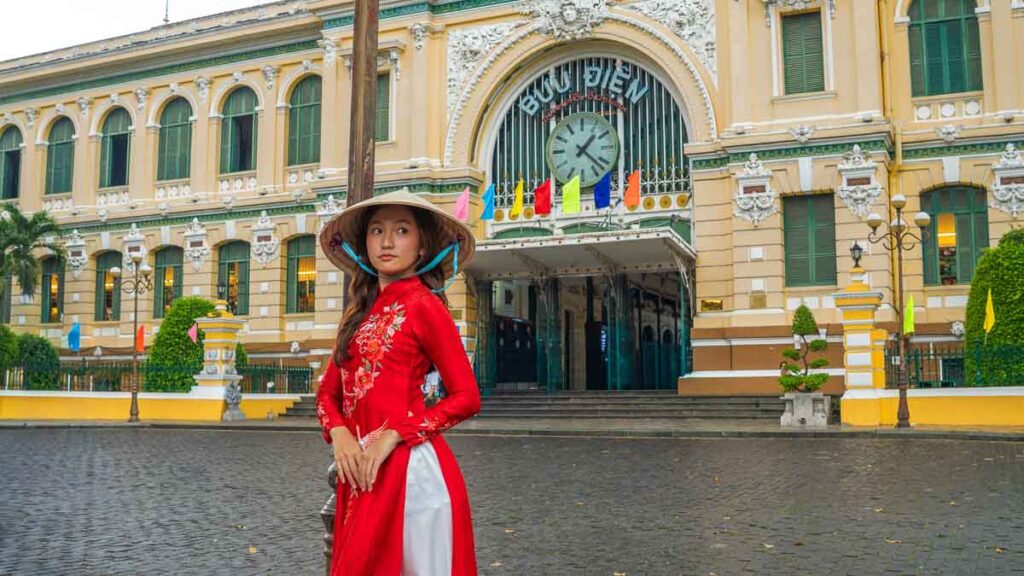 A lady standing in front of a post office - Ho Chi Minh City Budget Itinerary