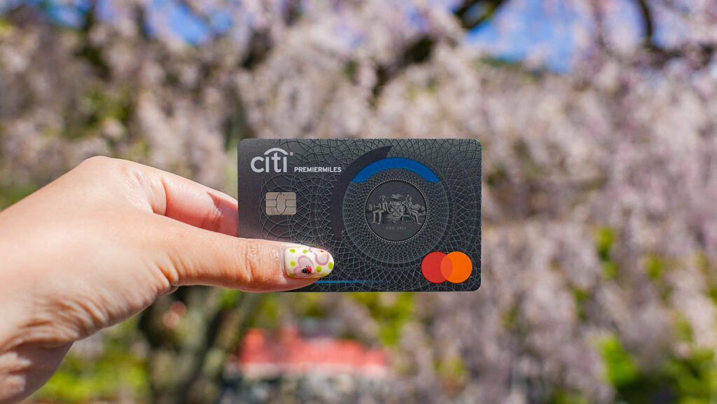 Credit card held against sakura background - Osaka for repeat travellers