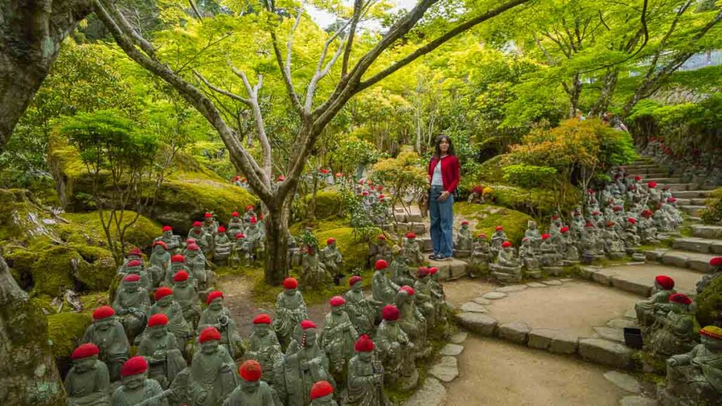 Girl standing in the middle of multiple stone statues - Hidden gems Osaka