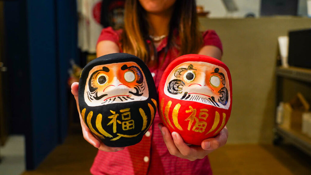 Girl holding Darumas - Things to do in Japan