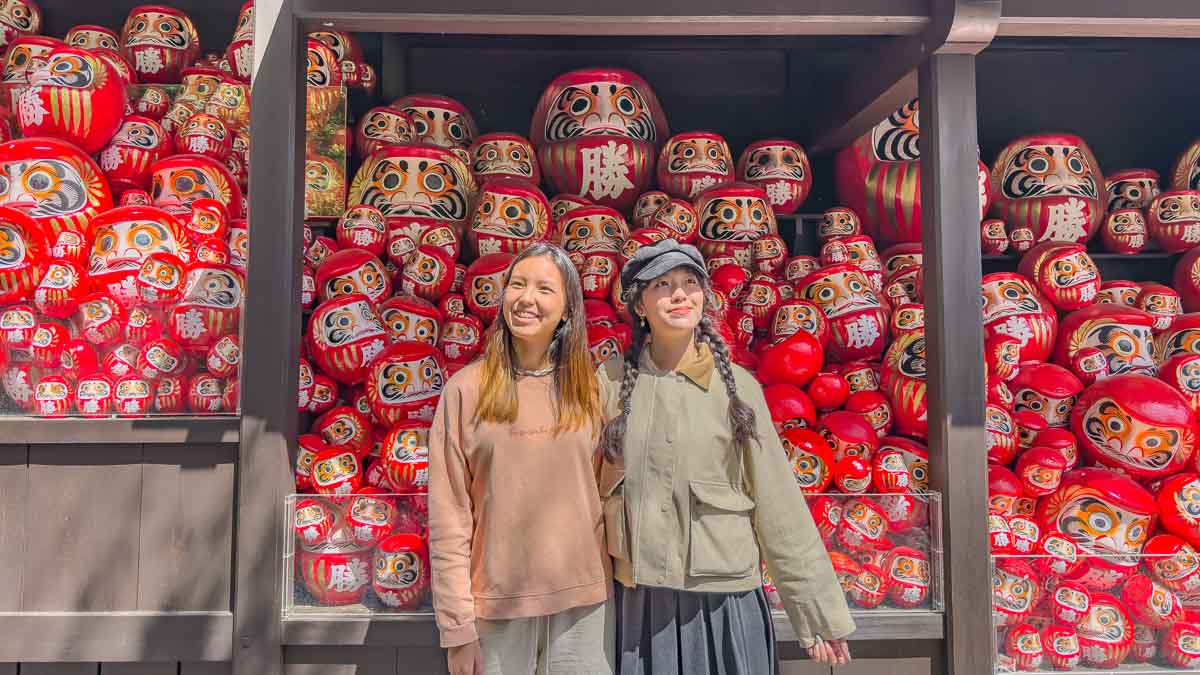 Girls in front of wall of Daruma - Osaka attractions