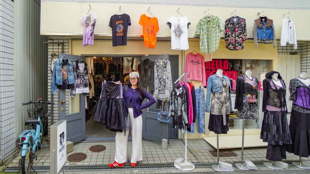 Girl holding up clothes in front of a clothing store - Hidden gems Osaka