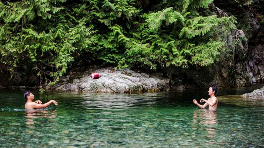 Boys throwing a football in a clear natural pool - Vancouver itinerary
