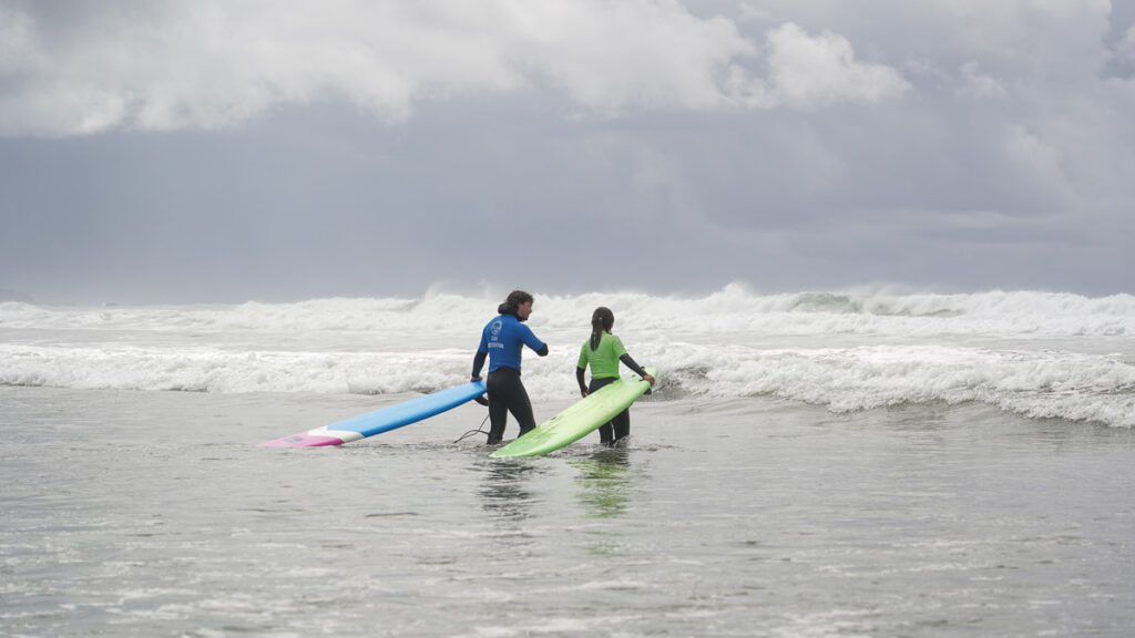 Girl and boy holding surfboards in the sea - First-timers in Vancouver